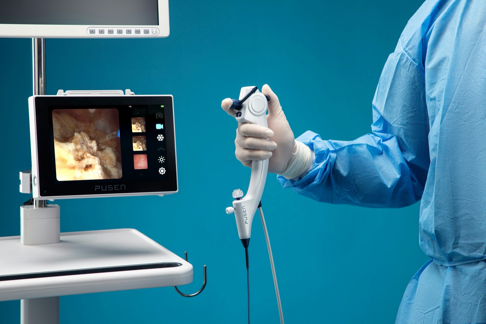 A clinician holding a flexible endoscope beside a monitor